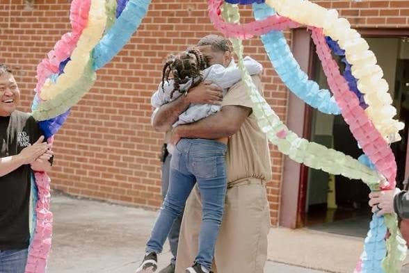 A man hugging a child under paper streamers