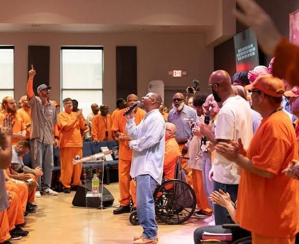 A worship service: a man sings into a microphone while people stand with hands raised